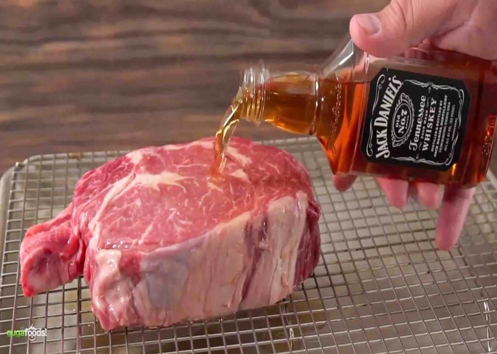 Pouring jack daniels whiskey to the steak