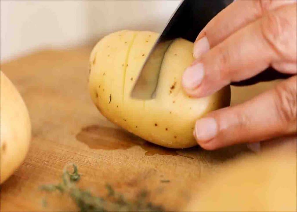 Slicing the potatoes, leaving a small part at the bottom unsliced