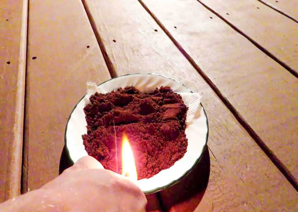 Lighting the paper towel pieces in the coffee ground for it to produce smoke