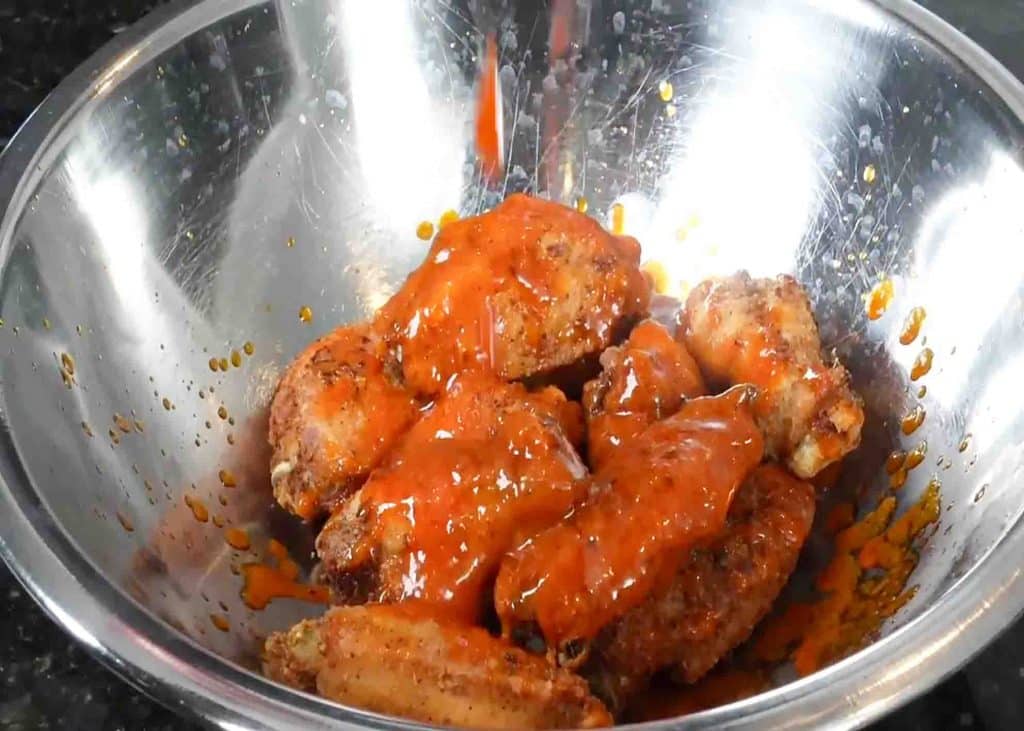 Pouring the hot sauce over the chicken wings