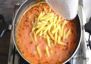 Adding the penne pasta into the sauce