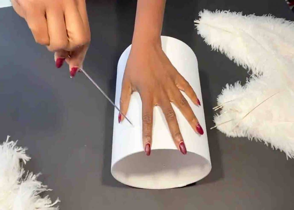 Poking holes to the lamp shade to attach the feathers