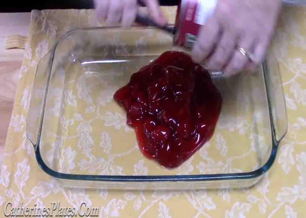 Adding the strawberry pie filling to the bottom of the baking dish