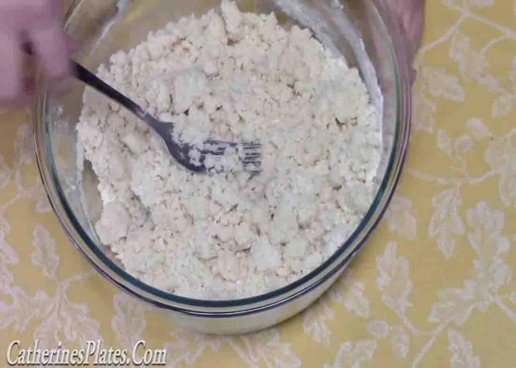 Mixing the cake mix and the butter to form a crumble consistency