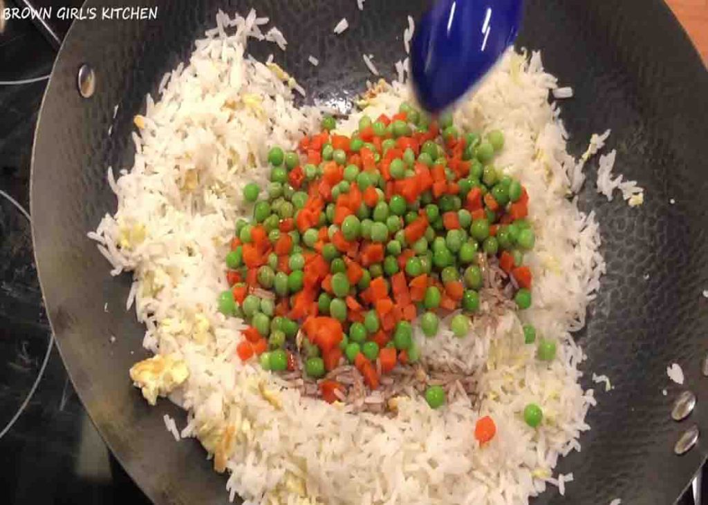 Adding the frozen peas and carrots to the fried rice