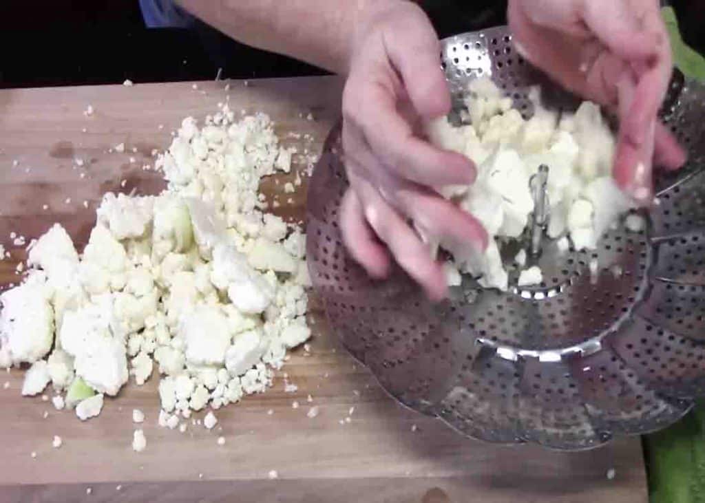 Transferring the chopped cauliflower to a steamer basket