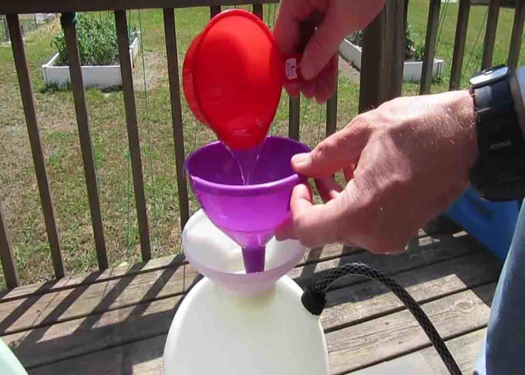 Pouring 1 cup of dishwashing liquid to the spray solution for the grass and weeds killer