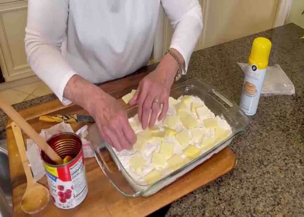 Adding the slices of butter over the top of the casserole dish