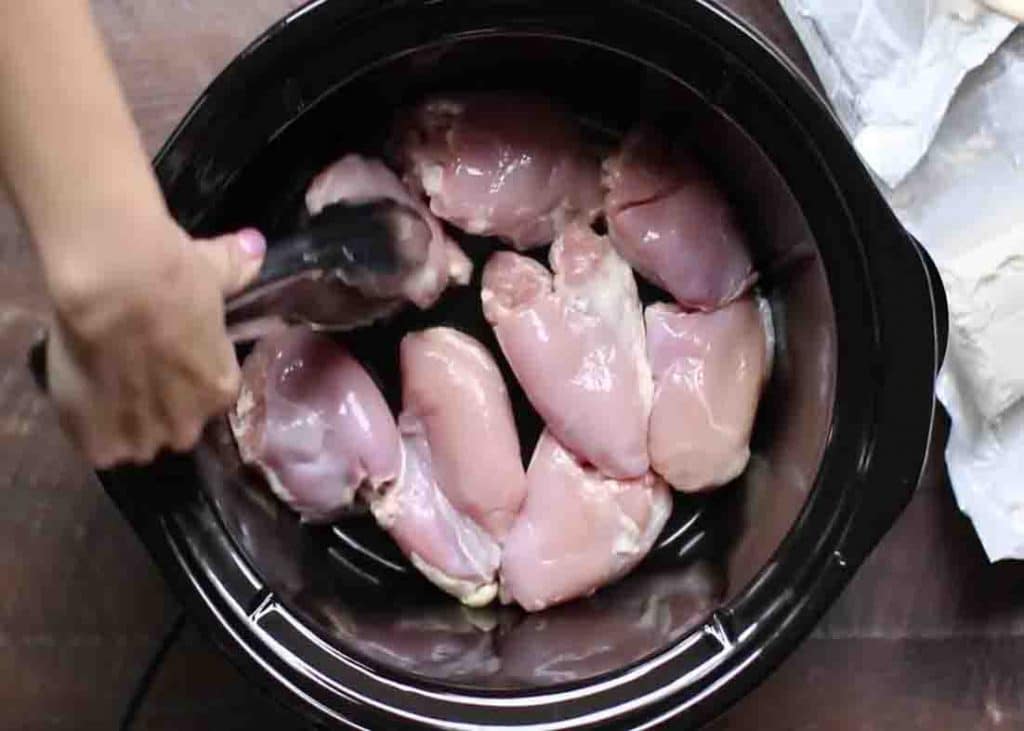 Placing the chicken thighs at the bottom of the slow cooker