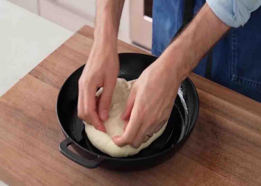 Placing the pizza dough on the cast-iron pan