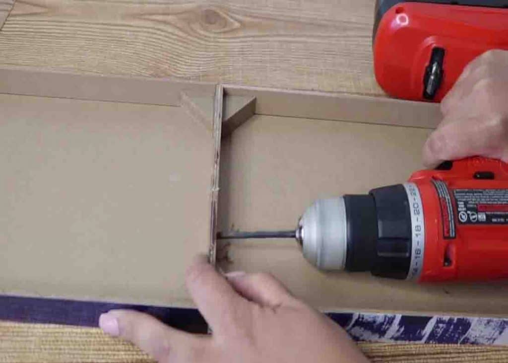 Drilling holes to the base board of the dollar tree shelf for extra security