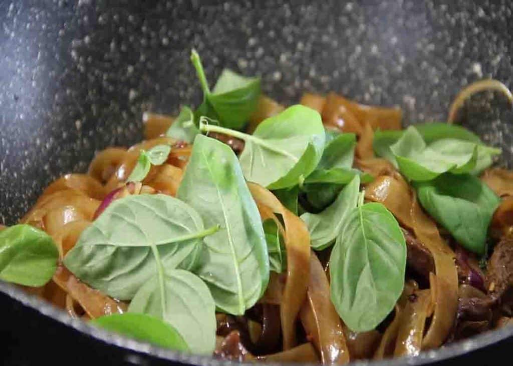 Adding some fresh basil to the drunken beef noodles