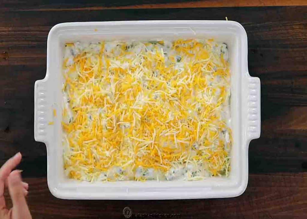 Finishing the Mexican chicken casserole by topping it with shredded cheese