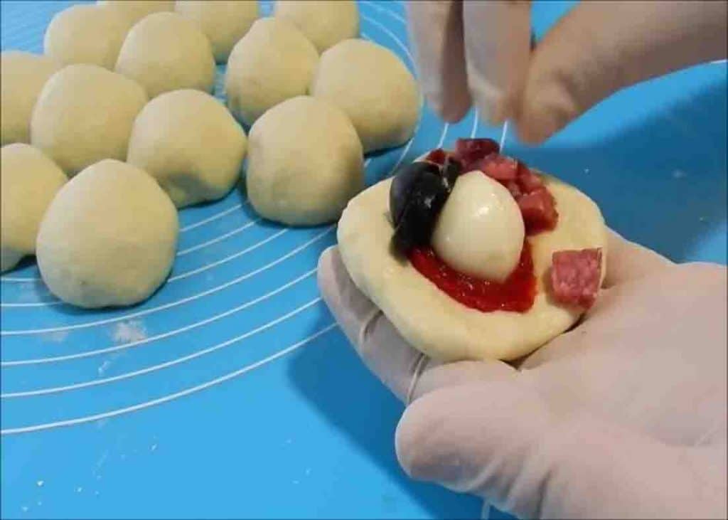 Adding the pizza filling to the dough