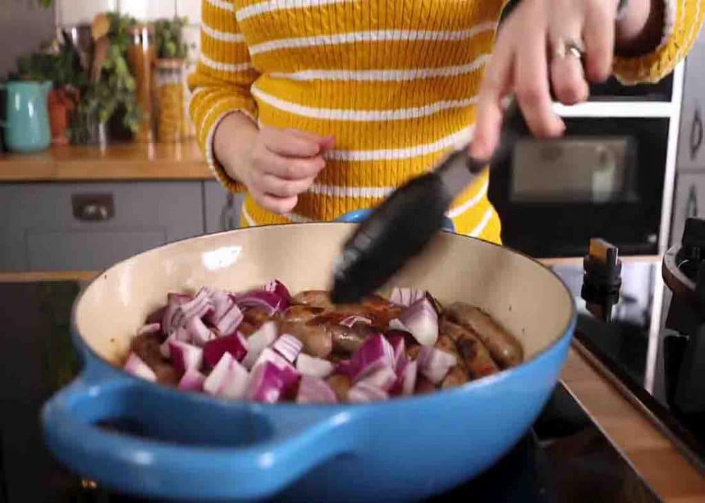 Cooking the diced red onion together with the sausage