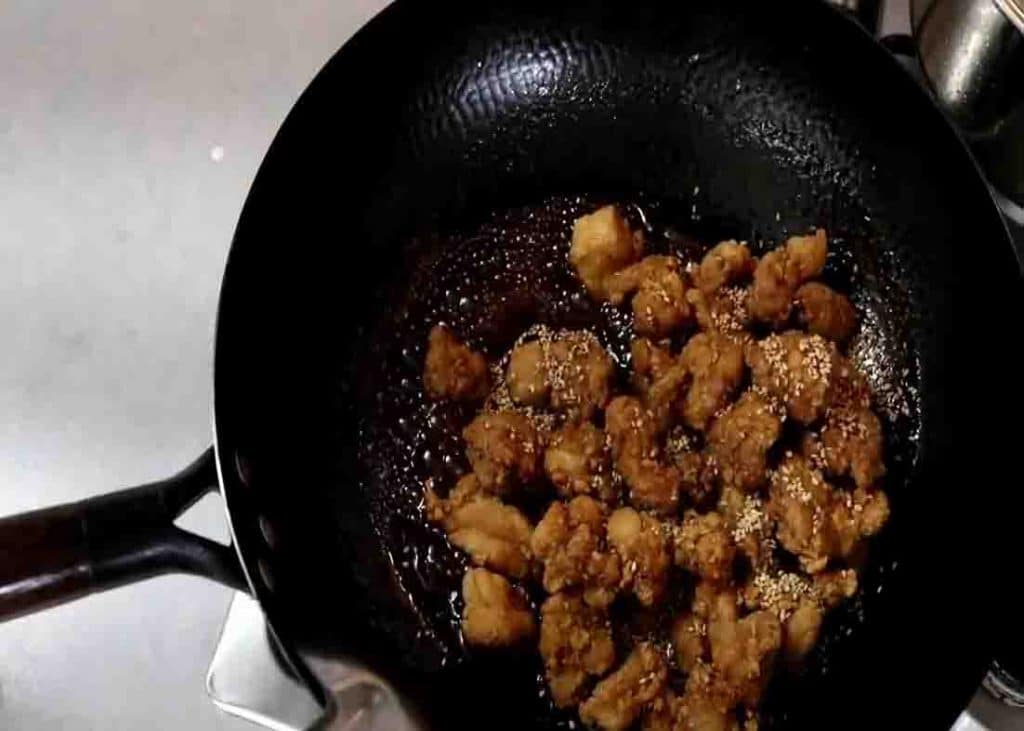 Coating the sesame chicken with the sauce
