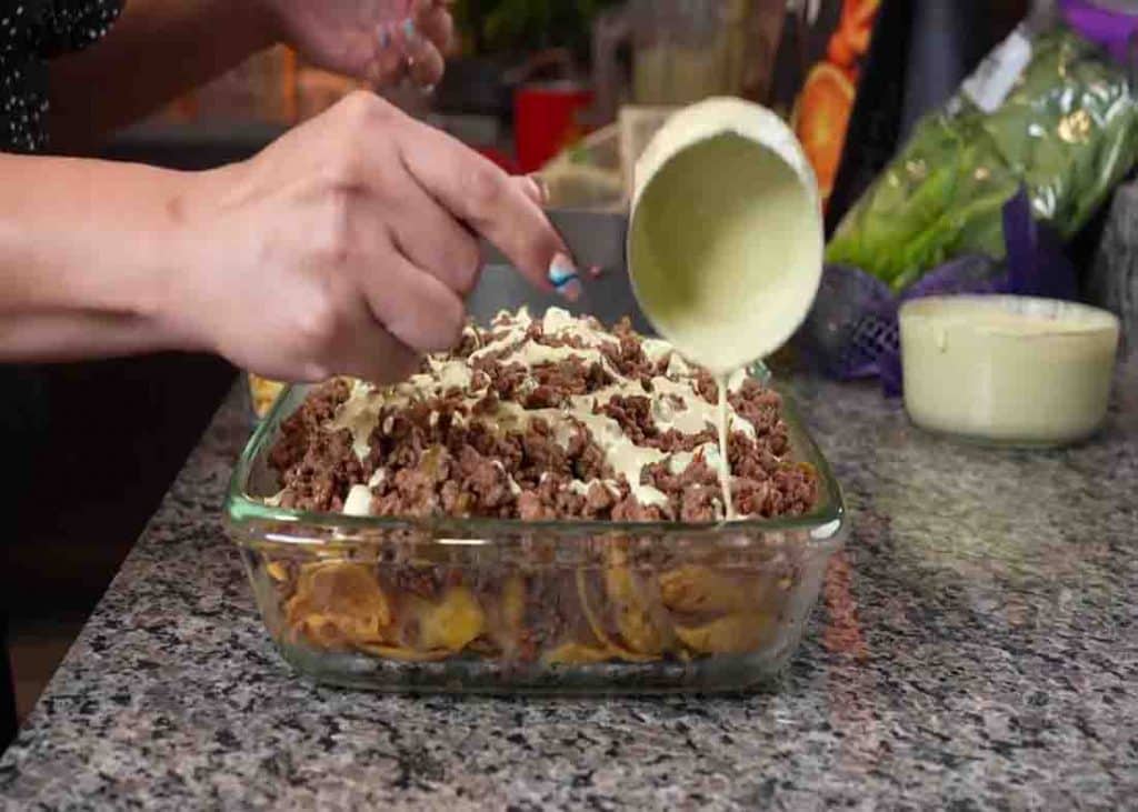 Adding the sauce to the walking taco casserole