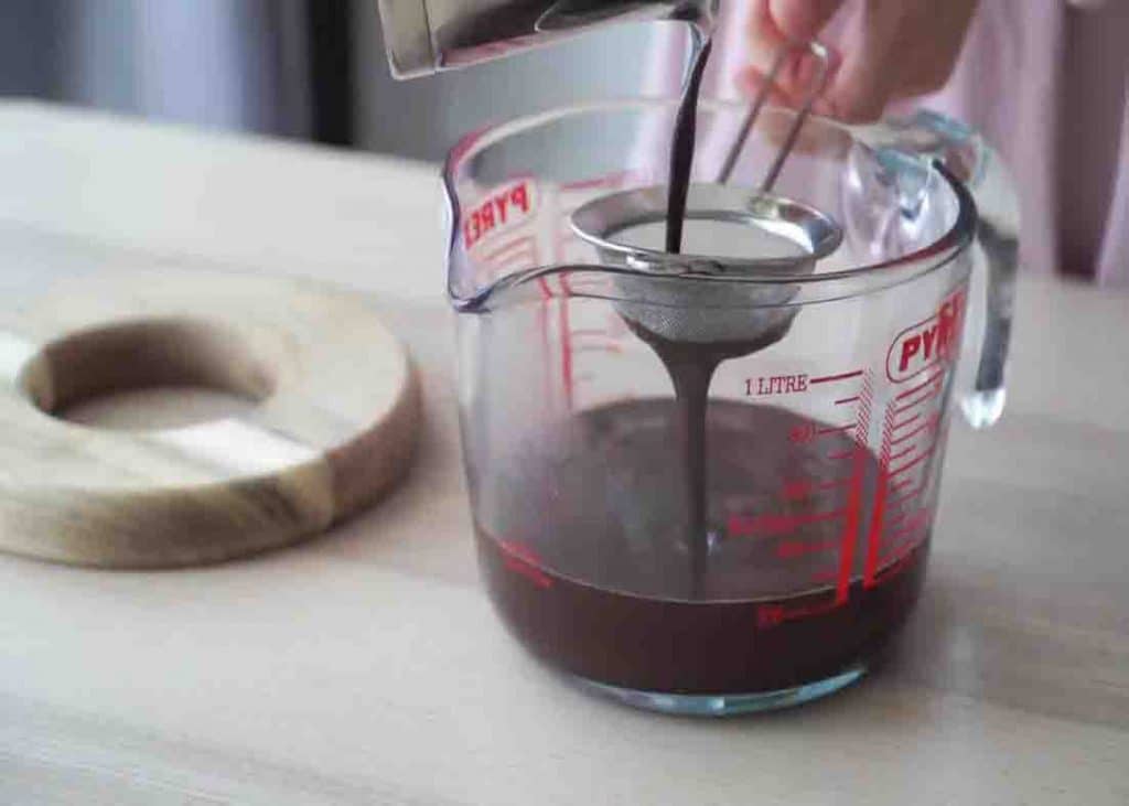 Sifting the chocolate glaze before pouring it to the cake