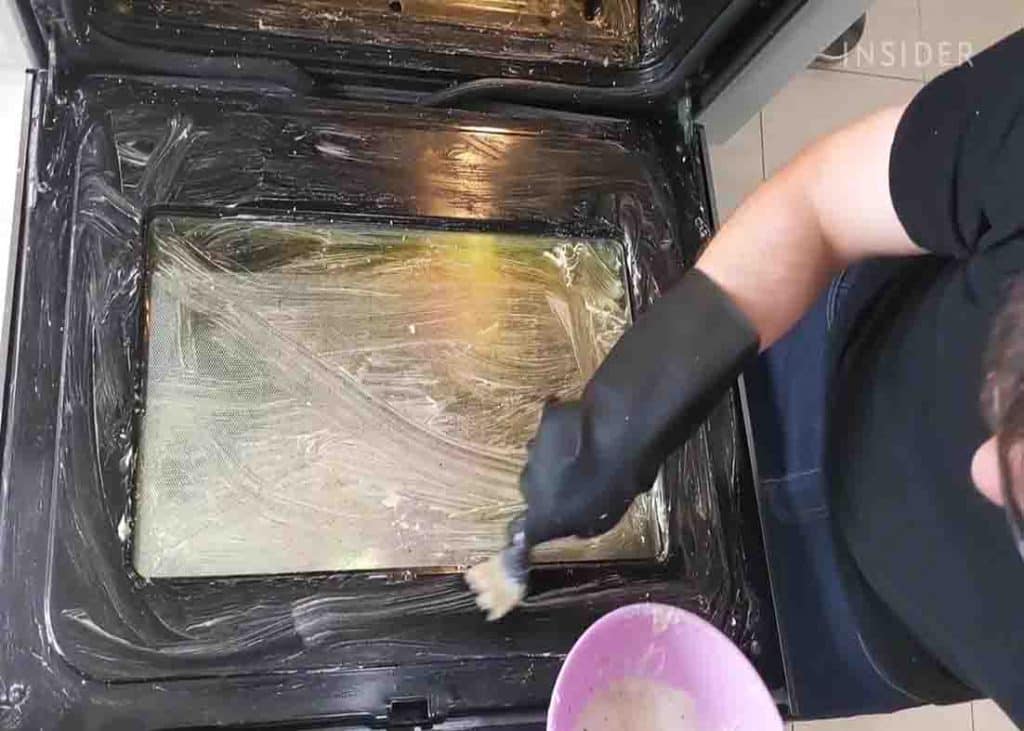 Spreading the paste mixture all over the insides of the oven