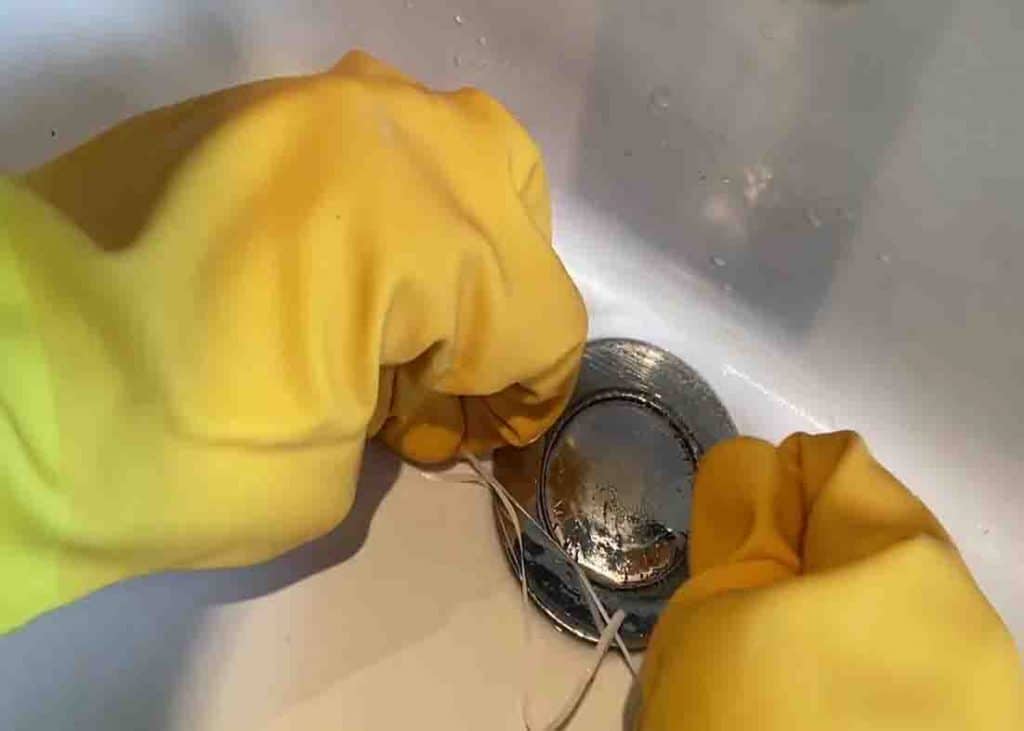 Pulling the dental floss strip hard to pop the sink plug up