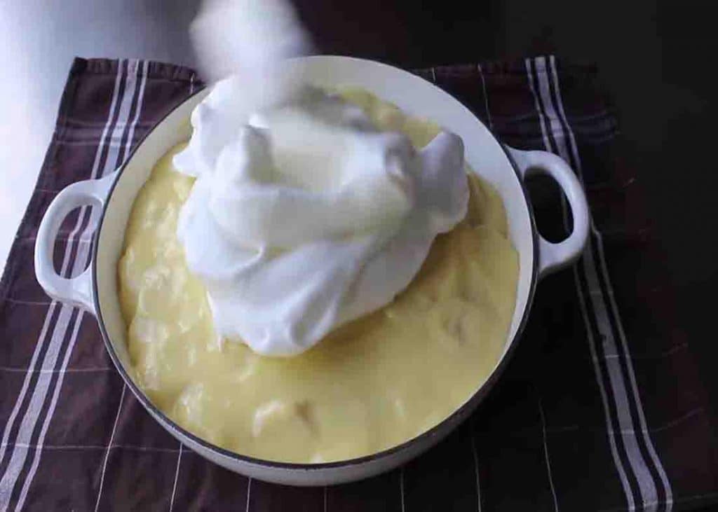 Adding the meringue on top of the banana pudding
