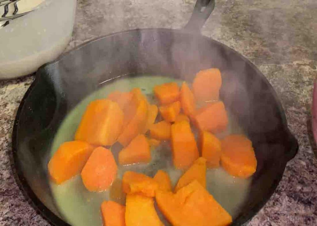 Adding the boiled sweet potatoes to the skillet with melted butter