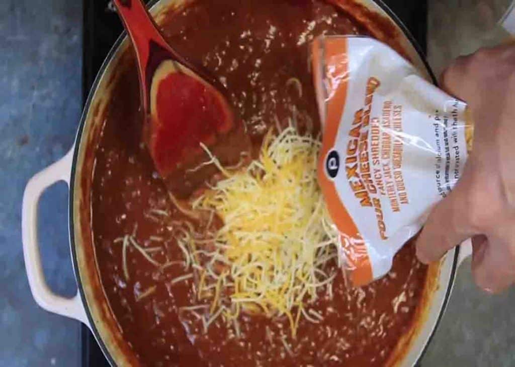 Adding the cheese to the chili cheese burrito sauce