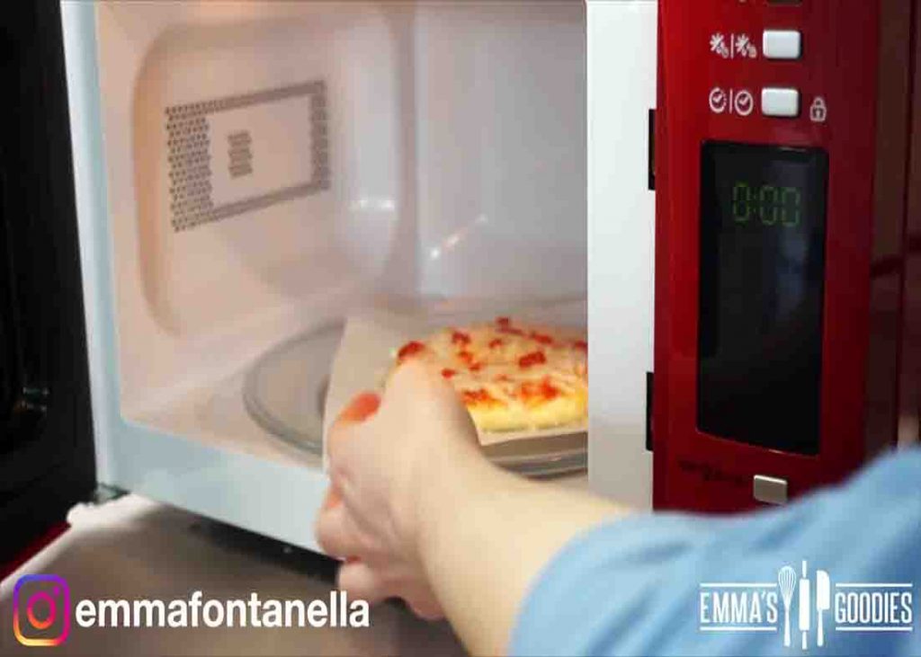 Placing the pizza to the microwave to cook it