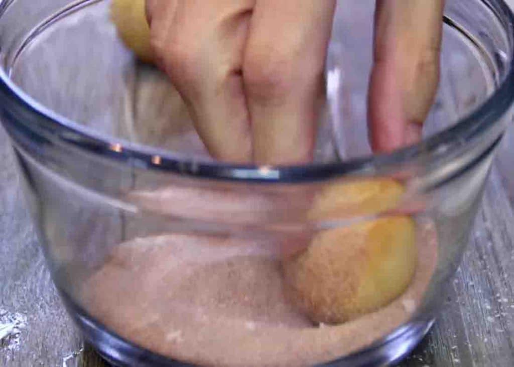 Coating the doughnuts with the cinnamon and sugar mixture