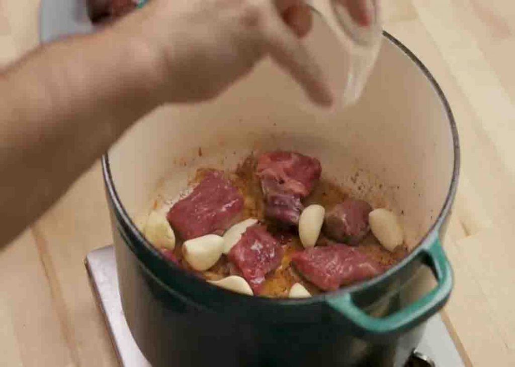 Searing the beef with garlic cloves