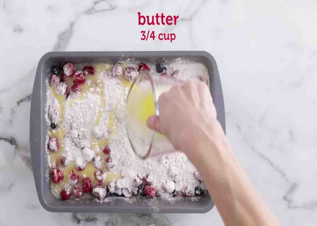Adding the melted butter over the mixed berry dump cake