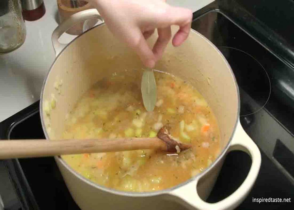 Adding bay leaf to the creamy homemade potato soup