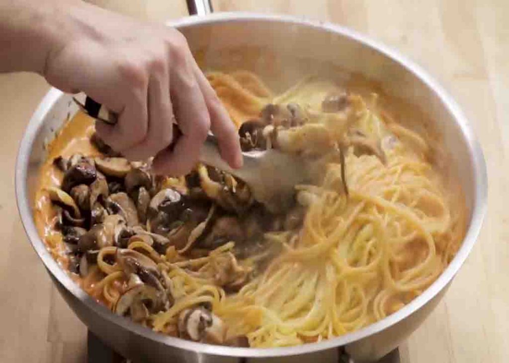 Tossing the spaghetti with the creamy mushroom sauce