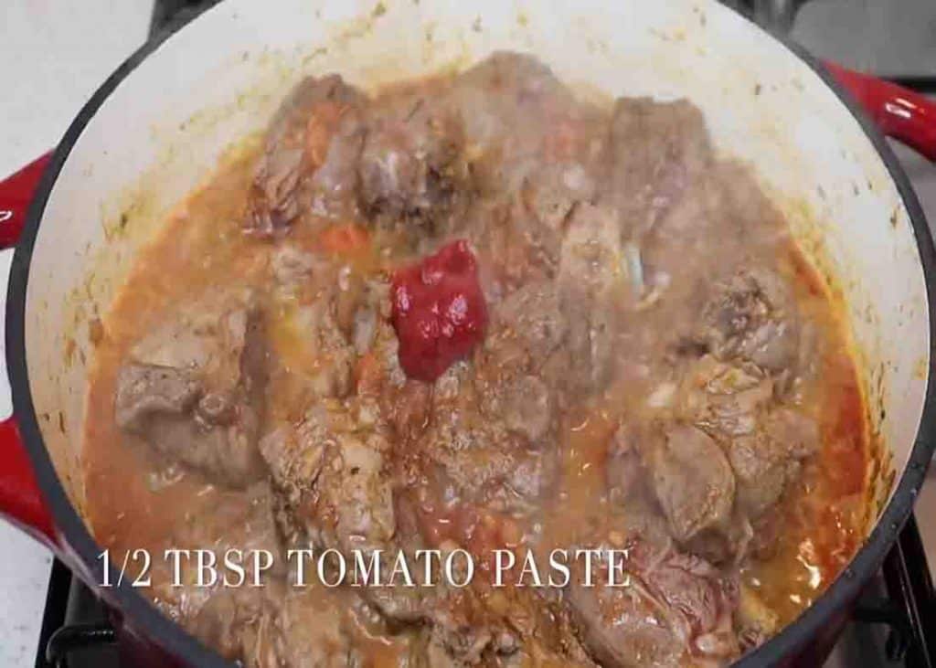 Adding the tomato paste to the lamb stew