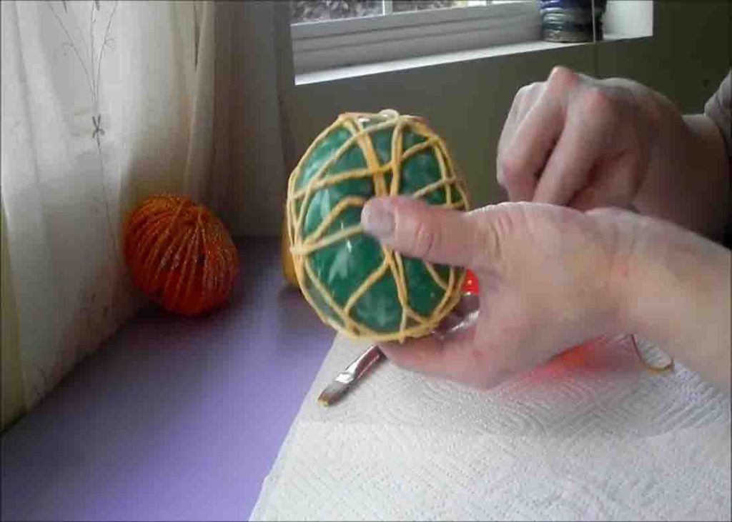 Wrapping the yarn to the balloon to make the pumpkin