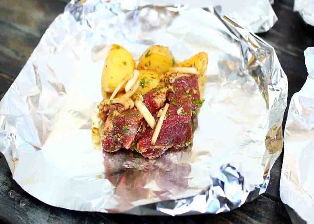 Distributing the steak and potatoes among the foil papers to be baked