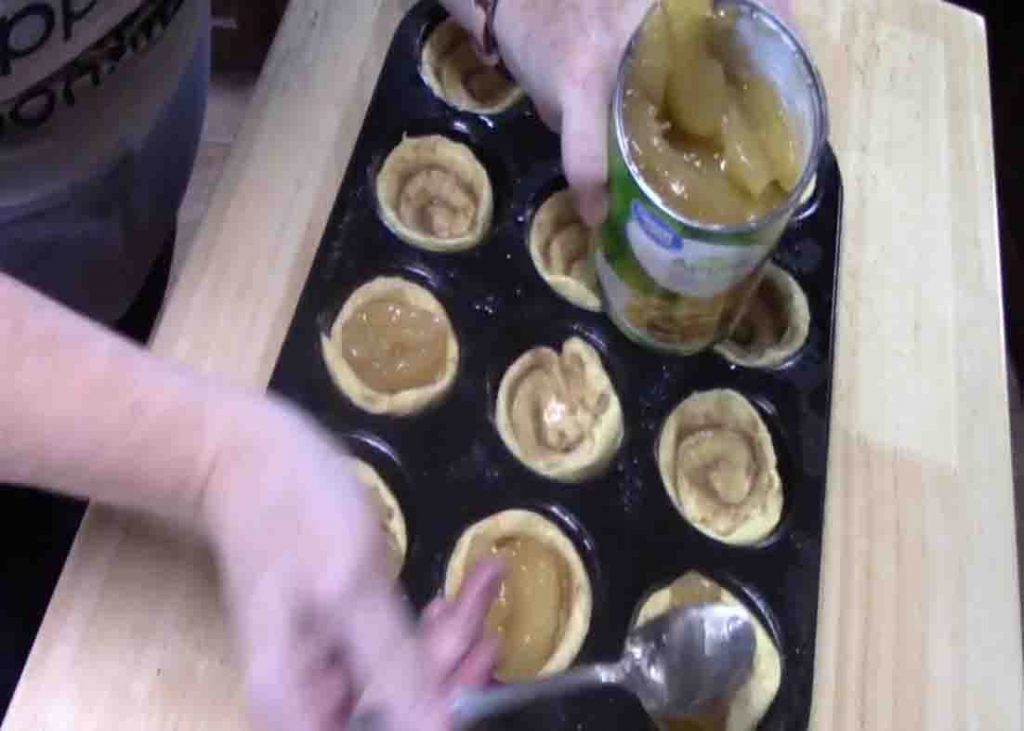 Putting the apple pie filling on top of each cinnamon roll