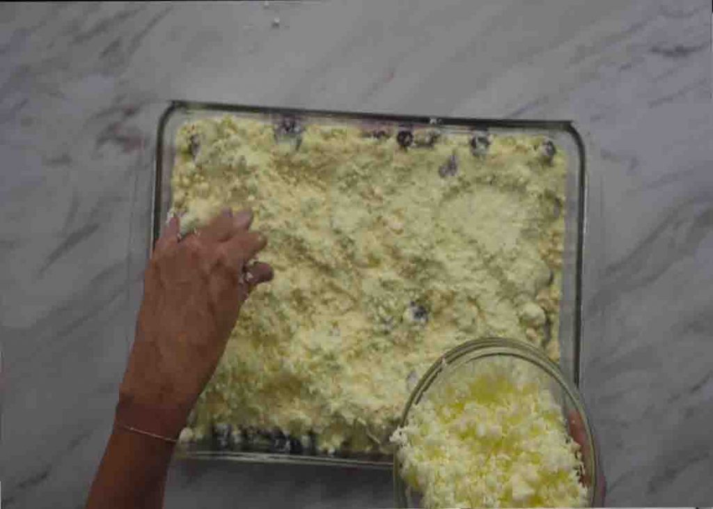 Sprinkling the grated butter over the berry dump cake