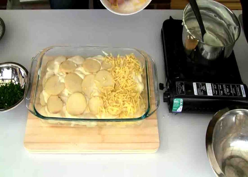 Assembling the cheesy scalloped potato casserole