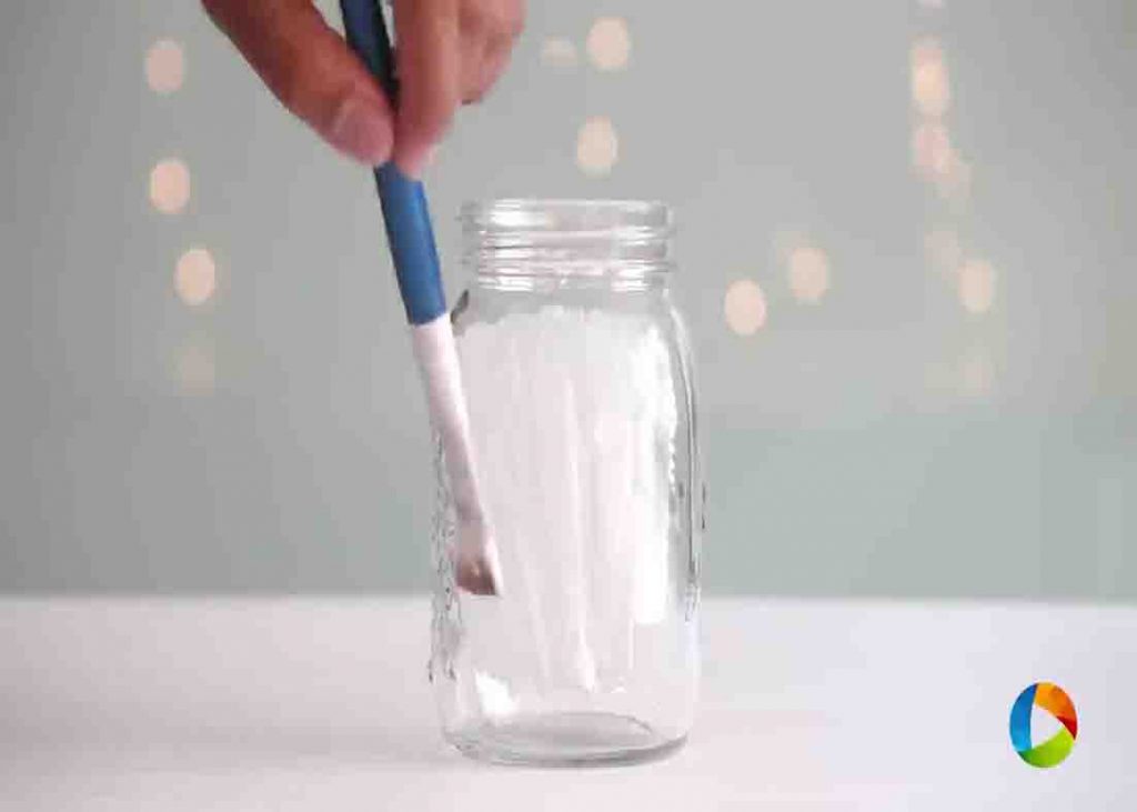 Putting glue around the jar to make the snowy mason jar