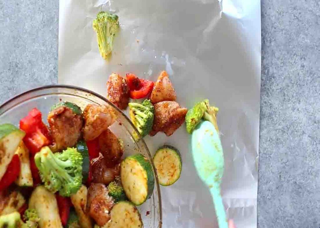 Putting the cajun chicken and veggies mixture to the foil sheets