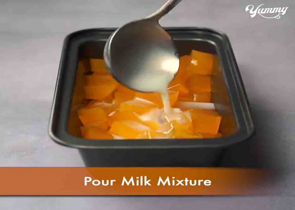 Adding the milk mixture over the orange jello pieces