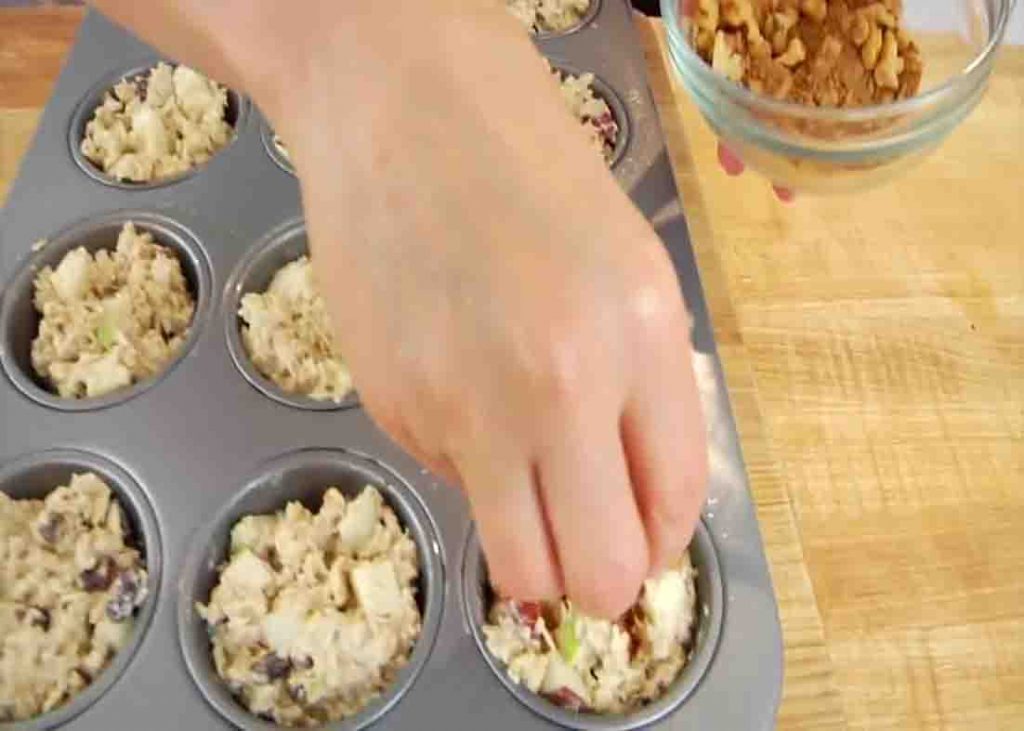 Distributing the apple oatmeal mixture into the muffin cups