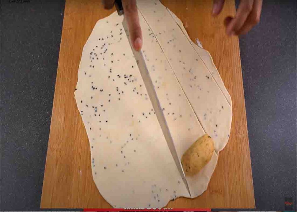 Rolling the log-shaped potato with the dough