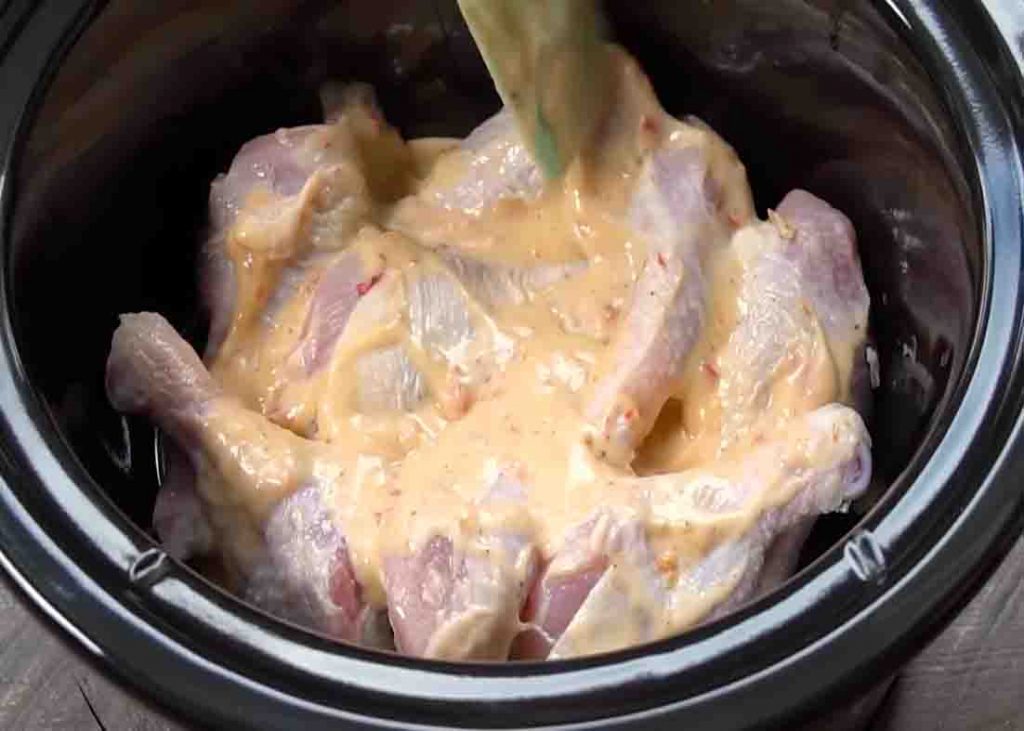 Pouring the bang bang chicken sauce over the chicken drumsticks