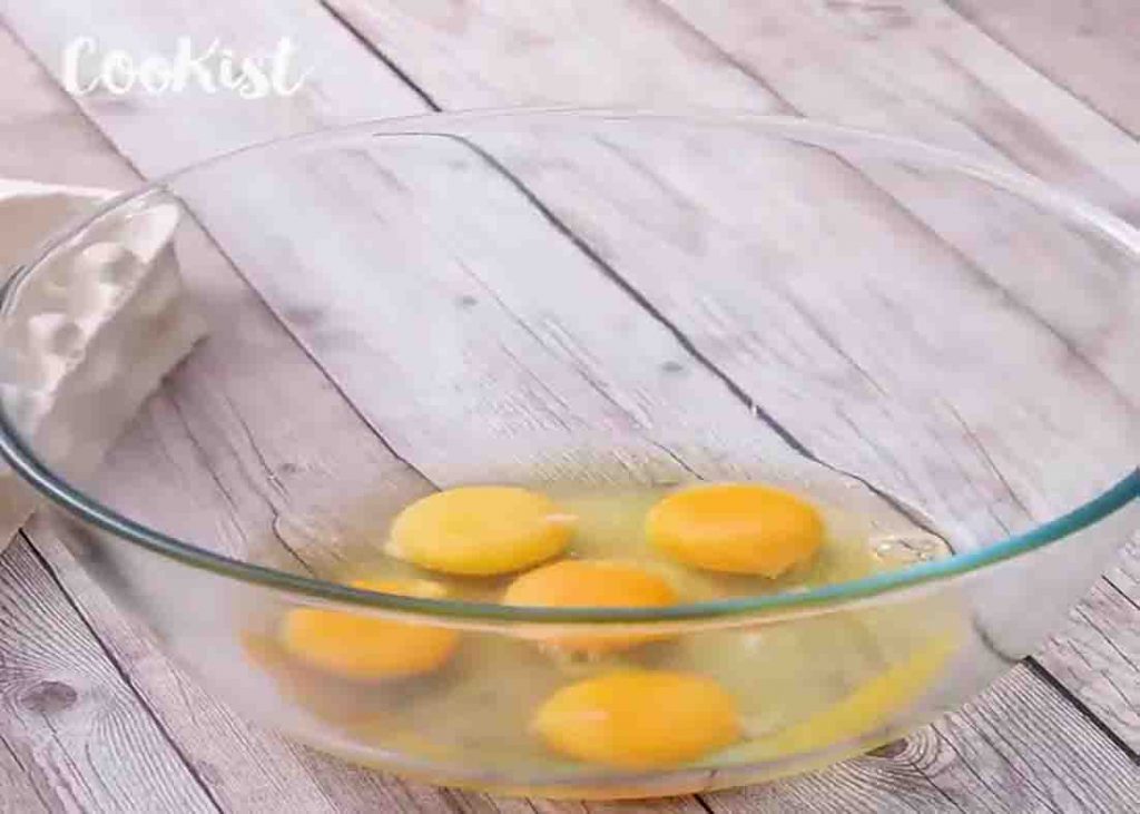 Cracking eggs in a bowl for the creamy cake recipe