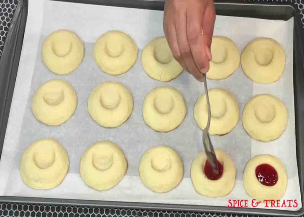 Adding the jam on top of each thumbprint cookie
