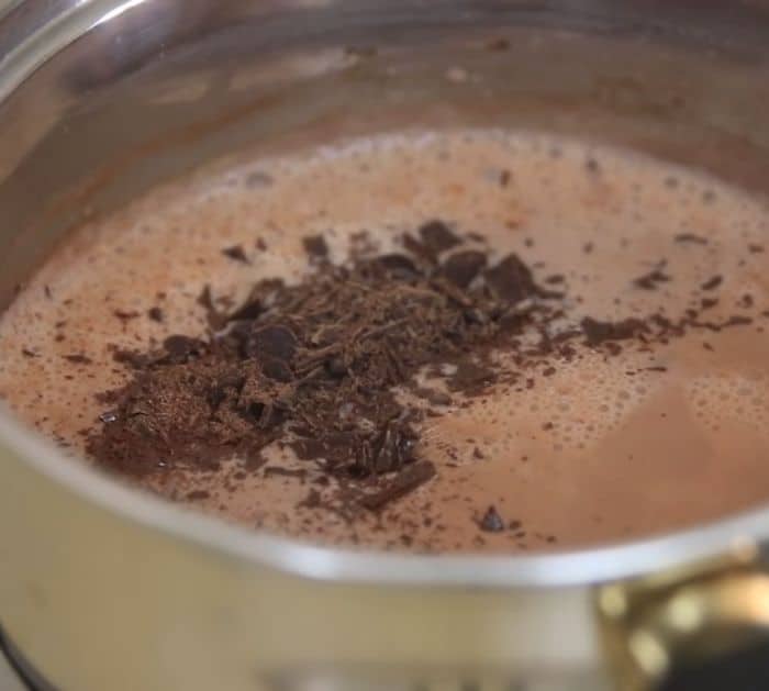 Boiling chocolate mixture on a pot with chopped chocolate