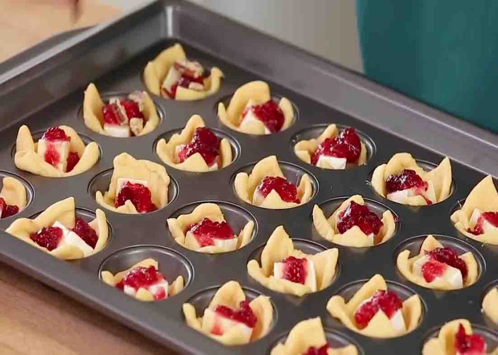 Putting cranberry sauce on each cranberry brie bites