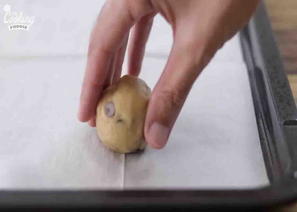 Placing the cookie to the parchment paper lined baking tray